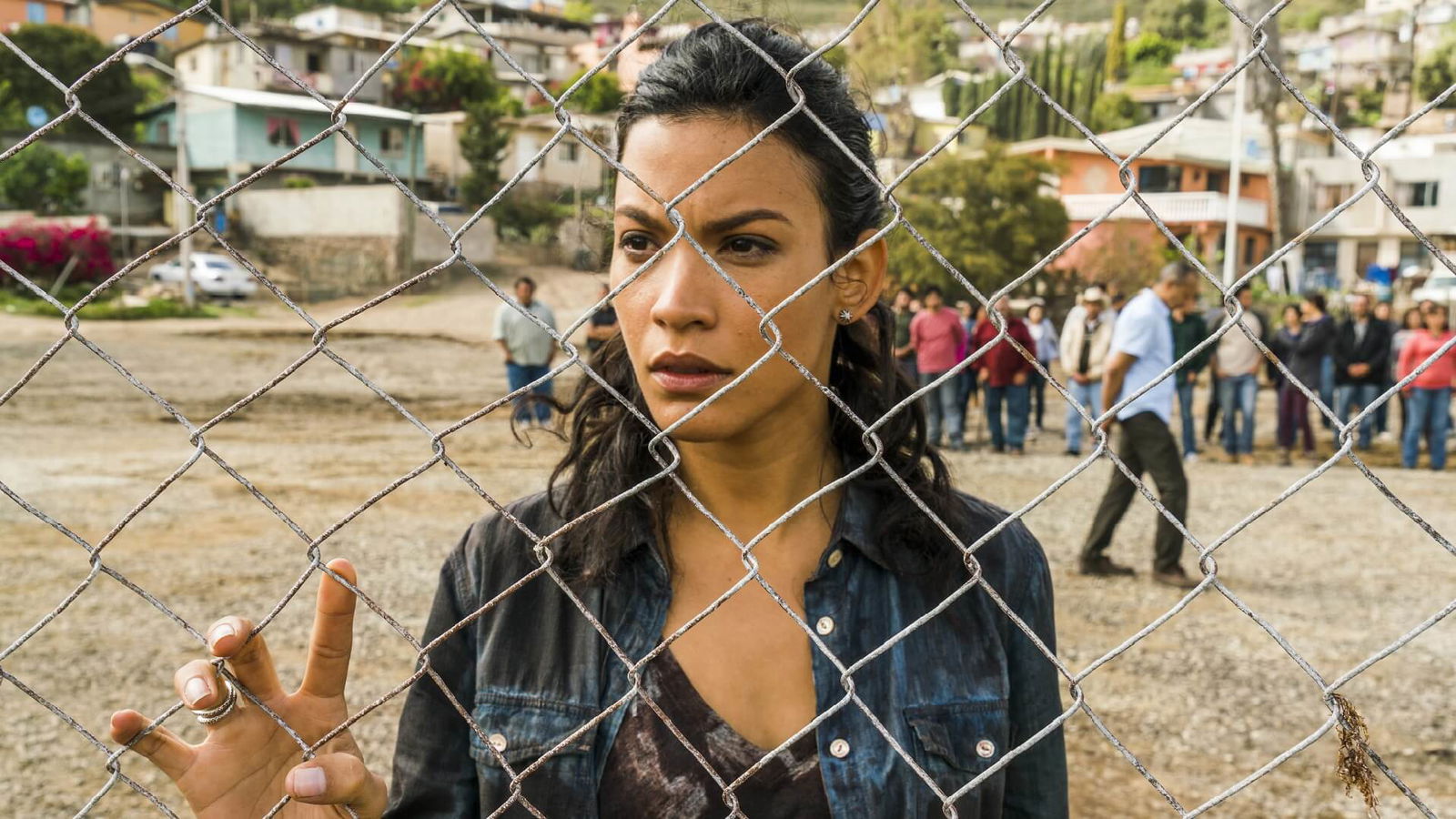 Luciana in Fear the Walking Dead looking through a fence at the infected