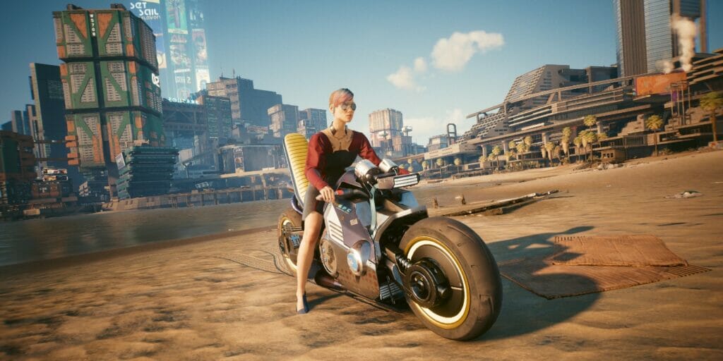 V sits on her motorcycle on the beach in Cyberpunk 2077