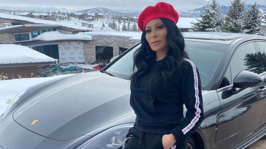 Jen Shah posing in a red beret and designer athleisure