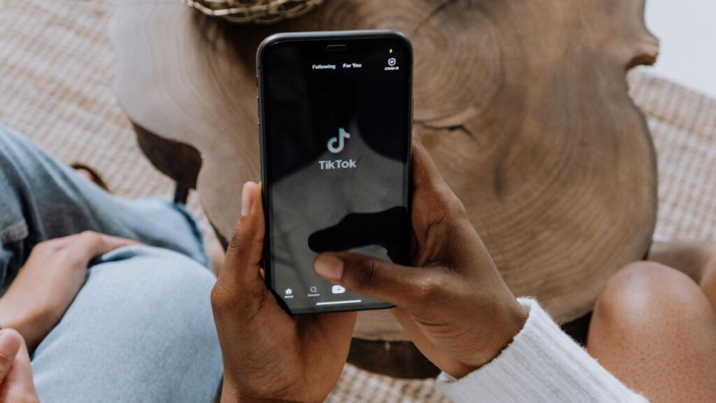 A hand holds a smartphone showing the TikTok app