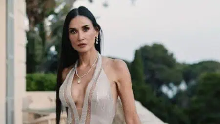 Film actress Demi Moore wears a beige dress and poses for a photo.