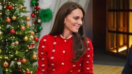 Kate Middleton seated in front of a Christmas tree during carol event.