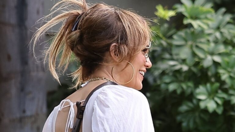 Jennifer Lopez smiles in a white dress.