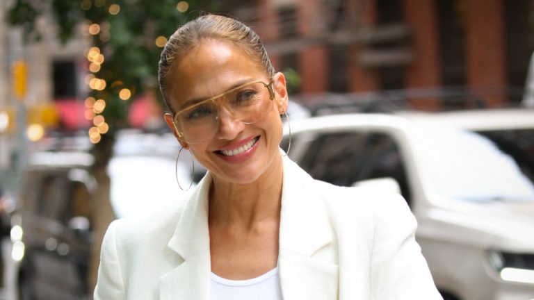 Jennifer Lopez smiles in white ensemble.