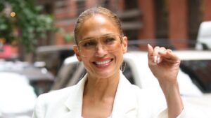 Jennifer Lopez smiles in white outfit.