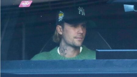 Justin Bieber wearing baseball cap and green sweater.