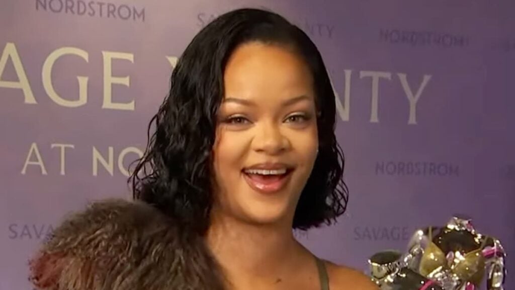 Rihanna smiling at a Fenty Beauty conference.