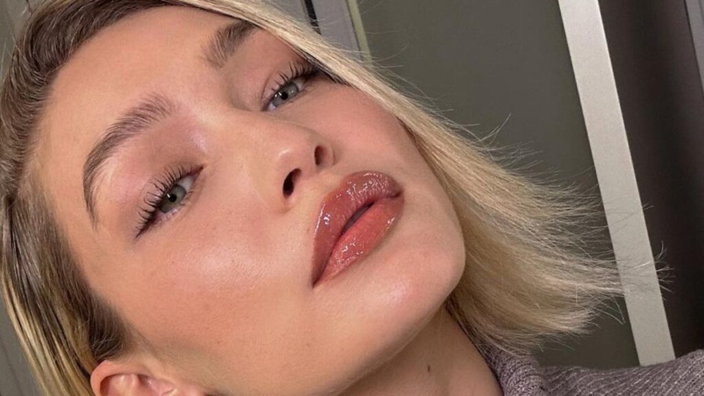 Gigi Hadid promoting Maybelline lip gloss in selfie.