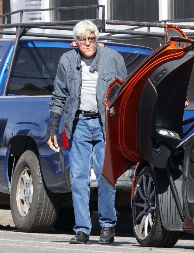 Jay Leno is pictured taking his 'vintage' orange Mclaren out after busting his face from a fall.