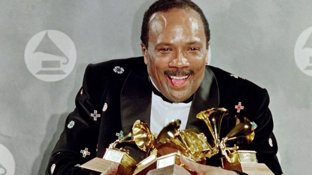 Quincy Jones clutching multiple awards in his arms