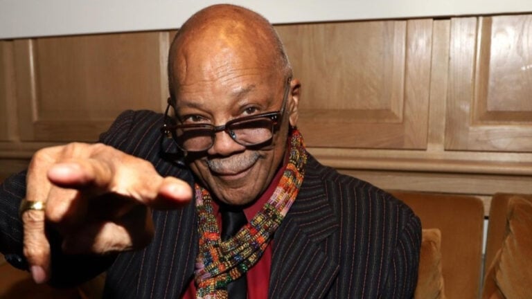 A close-up of Quincy Jones reaching toward the camera