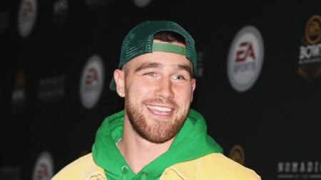 Travis Kelce smiling on the red carpet for an event.