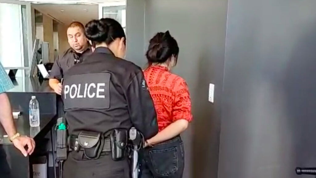 A police officer handcuffs someone protesting private prison company GEO Group and its plans to aid in the mass detention of U.S. immigrants