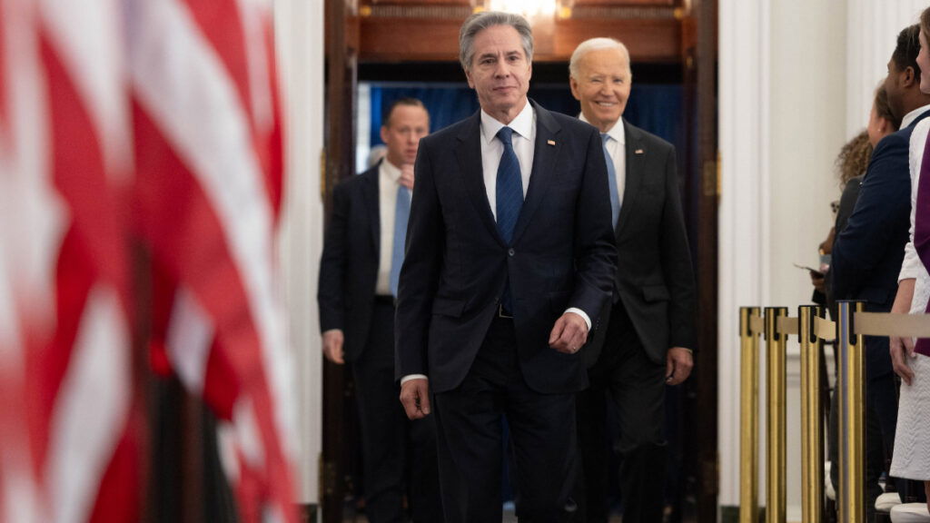 Secretary of State Antony Blinken walks with President Biden into a room