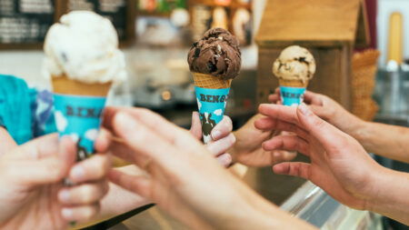 Three hands reach for ice cream cones during Ben & Jerry's Free Ice Cream Day