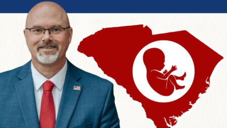 South Carolina State Rep. Rob Harris poses beside a picture of the state with a stylized baby inside