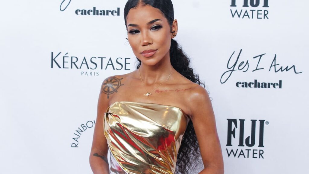 Jhene Aiko on the red carpet in a gold dress.