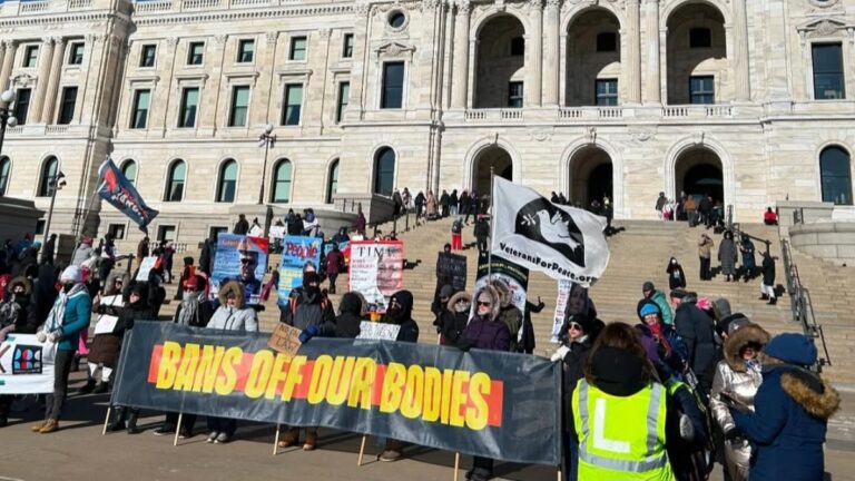 A crowd gathers to protest Trump at the People's March with a large banner reading "Bans Off Our Bodies"