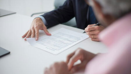 A man signs papers on a white table