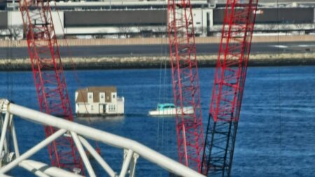 A boat tows a house through Boston Harbor