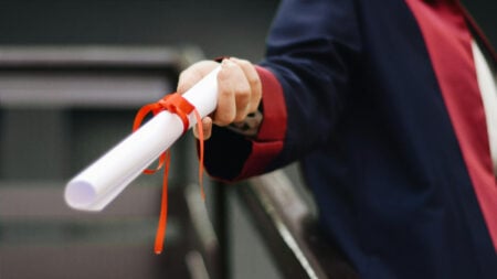 A college student holds a white scroll