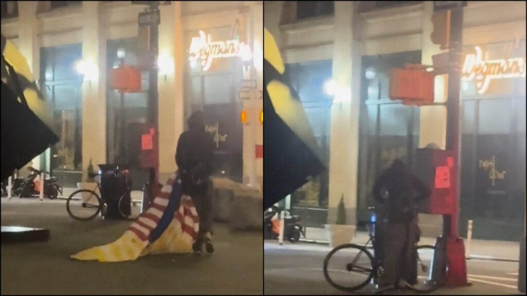 A person tears the U.S. / Ukraine flag off the NYC cube and stuffs it in the garbage