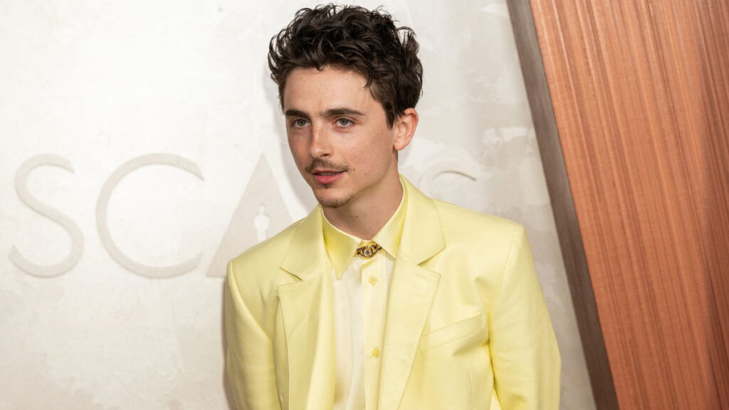 Timothée Chalamet attends the 2025 Oscars in a yellow outfit.