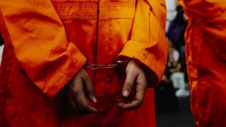 A man in handcuffs and orange jumpsuit