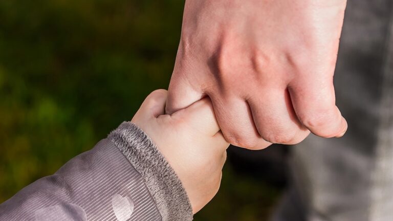 A parent holding their child's hand