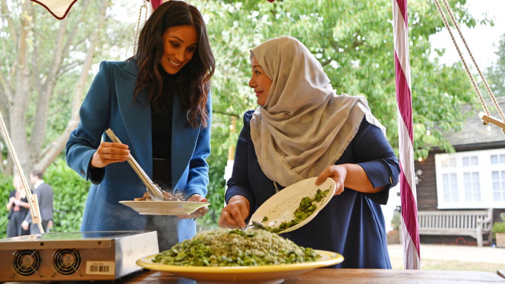 The duchess of Sussex Meghan Markle cooking alongside woman in hijab.