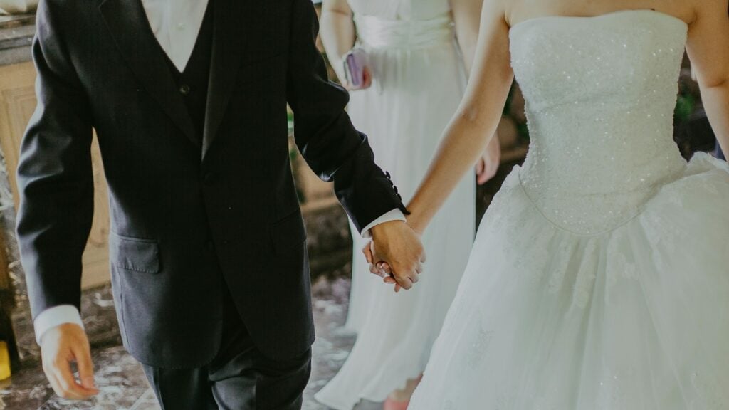a man and woman holding hands, at a wedding