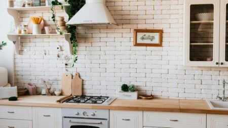 a kitchen with stove, counters, cutting boards, and shelves