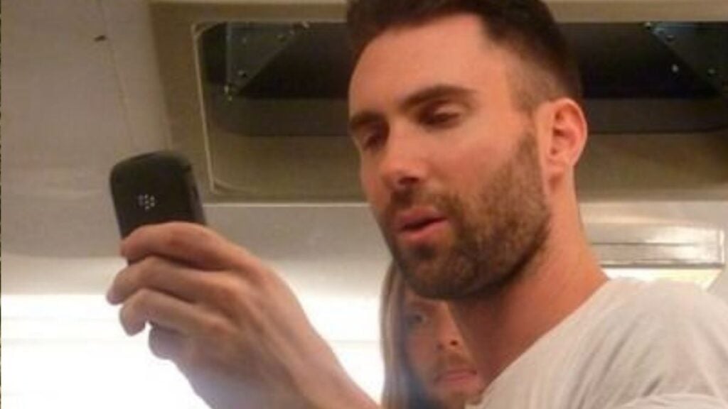 Adam Levine on his phone